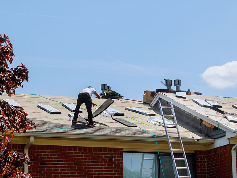 Contractor on top of residential roof installing asphalt shingles