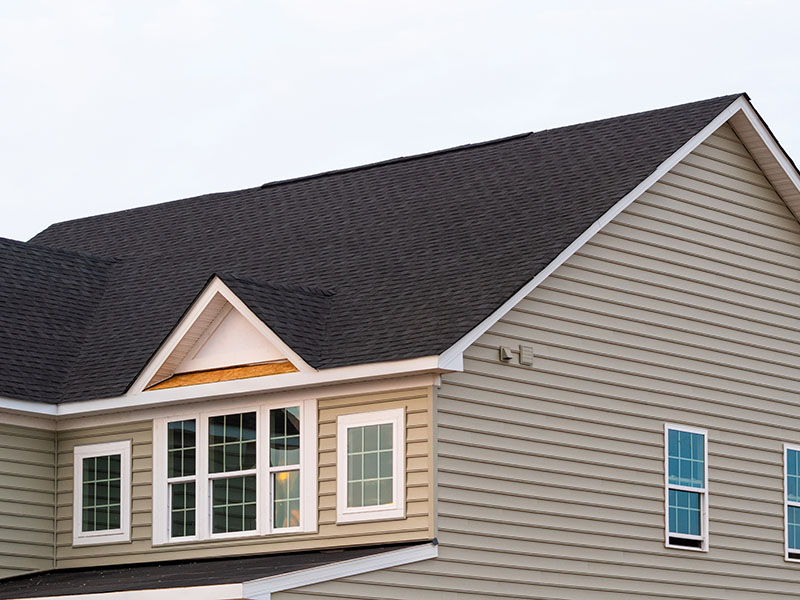 Close-up of a residential roof with charcoal asphalt shingles on it